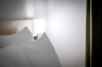 a room with a bed with a light on the wall at B:CONTE Asakusa in Tokyo