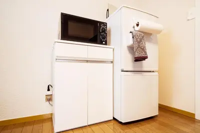 a white refrigerator with a microwave on top of it at Murata Corpo 305 in Tokyo