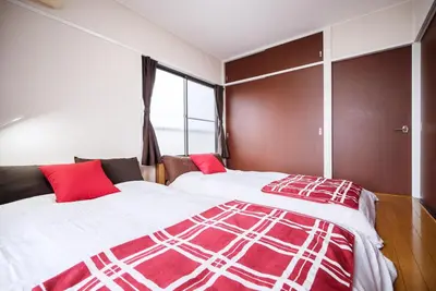 a bedroom with two beds with red pillows and a window at Murata Corpo 305 in Tokyo