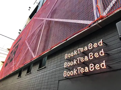a sign on the side of a building at Book Tea Bed SHINJUKU-GYOEN in Tokyo