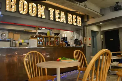 a table and chairs in a restaurant with a counter at Book Tea Bed SHINJUKU-GYOEN in Tokyo