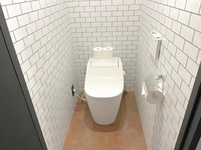 a bathroom with a toilet in a white tiled wall at Book Tea Bed SHINJUKU-GYOEN in Tokyo