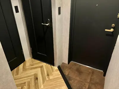 a hallway with two black doors and a wooden floor at Book Tea Bed SHINJUKU-GYOEN in Tokyo