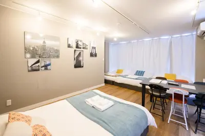 a room with two beds and a table in it at Maison Nagasaki 201 in Tokyo