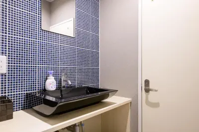 a black sink in a bathroom with blue tiles at Maison Nagasaki 201 in Tokyo