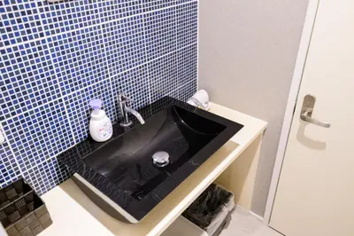 a black sink in a bathroom with blue tiles at Maison Nagasaki 201 in Tokyo