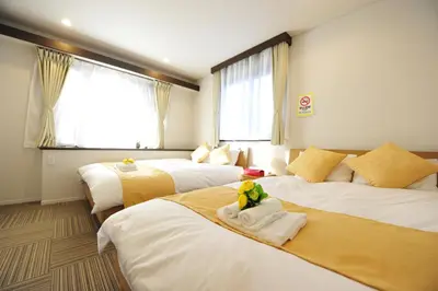 a hotel room with three beds with towels on them at Asakusa Kei House in Tokyo