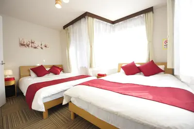 two beds in a hotel room with a window at Asakusa Kei House in Tokyo