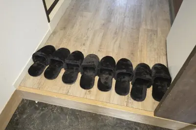 a row of black shoes on a wooden shelf at Roppongi WoodsHouse501 in Tokyo