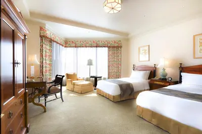 a hotel room with two beds and a desk at Hotel Chinzanso Tokyo in Tokyo