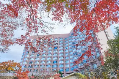 a tall building with red leaves in front of it at Hotel Chinzanso Tokyo in Tokyo
