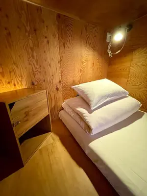 a small room with a bed and a night stand at Nomad Hostel Classic in Tokyo