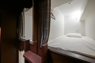 a small bed in a small room with a open door at bnb+ Ueno Okachimachi in Tokyo
