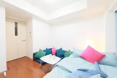 a living room with a blue couch with colorful pillows at IBASHO ShibuyaDogenzaka803 in Tokyo