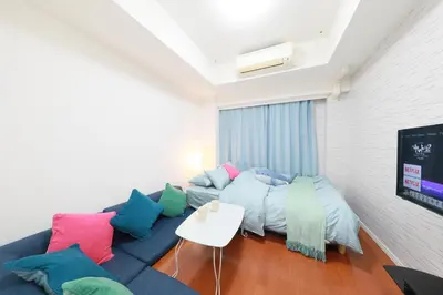 a living room with a blue couch with colorful pillows at IBASHO ShibuyaDogenzaka803 in Tokyo