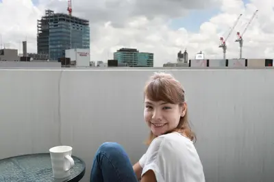 a girl sitting on a ledge with a cup of coffee at IBASHO ShibuyaDogenzaka810 in Tokyo