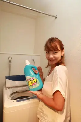a woman holding a bottle of laundry detergent next to a washing machine at IBASHO ShibuyaDogenzaka907 in Tokyo
