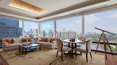 a living room with a table and chairs and a large window at The Peninsula Tokyo in Tokyo