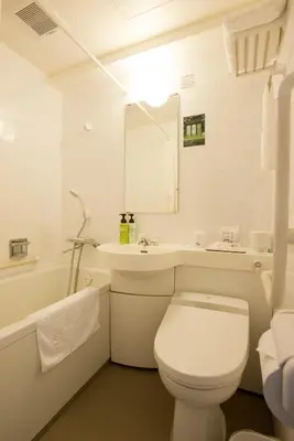 a white bathroom with a toilet and a sink at Kadoya Hotel in Tokyo