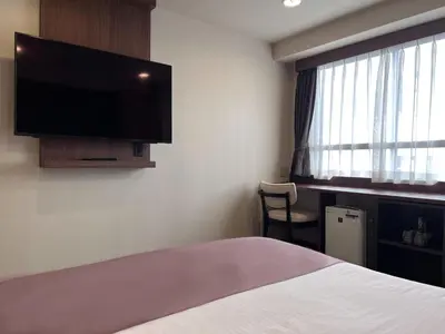 a hotel room with a bed and a flat screen tv at Kadoya Hotel in Tokyo