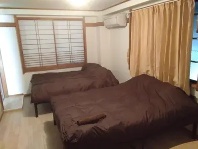 two beds in a room with a window at Nice Hostel Kameari in Tokyo