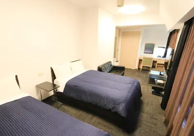 a hotel room with two beds and a desk at HOTEL LiVEMAX BUDGET Shinbashi in Tokyo