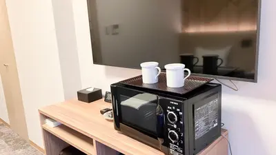 a microwave with two cups sitting on top of it at HOTEL LiVEMAX BUDGET Shinbashi in Tokyo