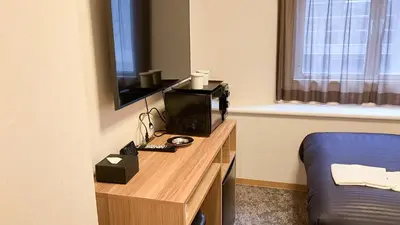 a room with a desk with a television and a bed at HOTEL LiVEMAX BUDGET Shinbashi in Tokyo