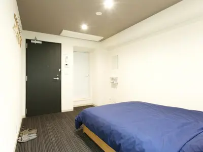 a bedroom with a blue bed and a black door at Hotel Cocoro Inn Asakusa Kuramae in Tokyo