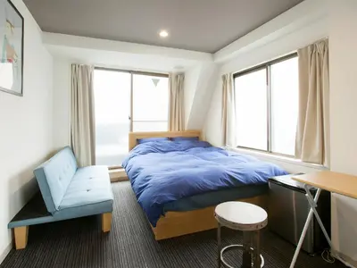 a bedroom with a bed and a chair and windows at Hotel Cocoro Inn Asakusa Kuramae in Tokyo
