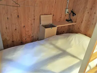 a bed in a room with a wooden wall at Hostel Bedgasm in Tokyo