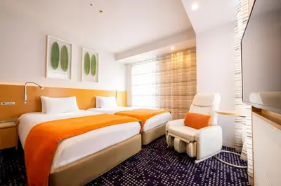 a hotel room with two beds and a chair at remm Hibiya in Tokyo