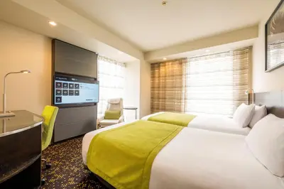 a hotel room with a large bed and a desk at remm Hibiya in Tokyo