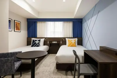 a hotel room with two beds and a table at Four Points Flex by Sheraton Tokyo Shibuya West in Tokyo