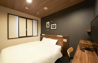 a bedroom with a white bed and a television at Sotetsu Fresa Inn Nihombashi Kayabacho in Tokyo
