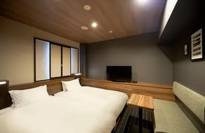 a bedroom with two beds and a flat screen tv at Sotetsu Fresa Inn Nihombashi Kayabacho in Tokyo