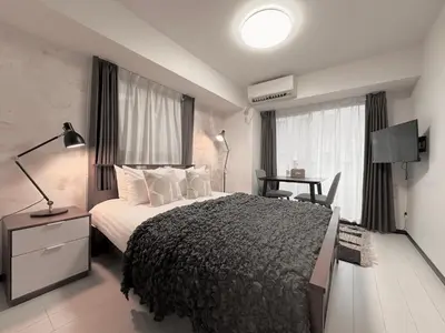 a bedroom with a bed and a desk with a lamp at LANG Hotel GINZA 1K in Tokyo