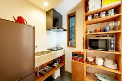 a kitchen with a stainless steel refrigerator and wooden shelves at plat hostel keikyu asakusa karin in Tokyo