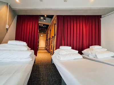 a row of beds in a room with a red curtain at UNPLAN Shinjuku in Tokyo