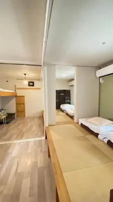 two beds in a room with wooden floors and ceilings at Den 7 in Tokyo