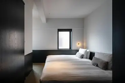 a bedroom with two beds in a room with a window at DDD HOTEL in Tokyo
