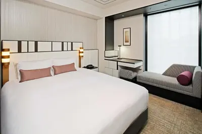 a bedroom with a large white bed and a chair at KOKO HOTEL Premier Nihonbashi Hamacho in Tokyo