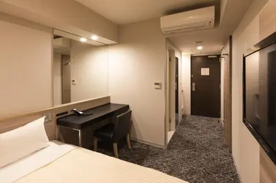 a bedroom with a desk and a bed and a mirror at Sotetsu Fresa Inn Shimbashi Hibiyaguchi in Tokyo