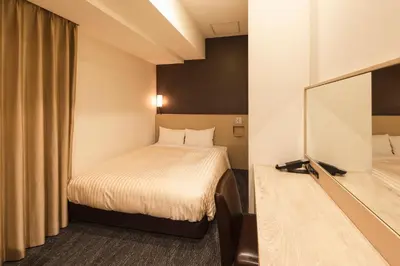 a hotel room with a bed and a mirror at Sotetsu Fresa Inn Shimbashi Hibiyaguchi in Tokyo
