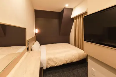 a hotel room with two beds and a flat screen tv at Sotetsu Fresa Inn Shimbashi Hibiyaguchi in Tokyo