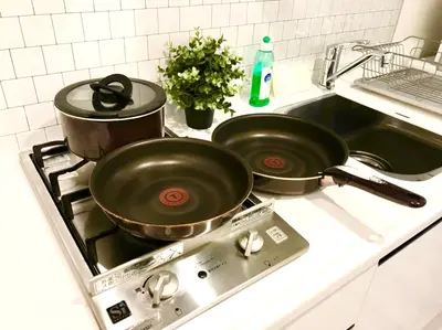two pans sitting on top of a kitchen stove at \u30ea\u30d6\u30b7\u30c6\u30a3\u9326\u7cf8\u753a\u53c2\u756a\u9928\u4e0a\u5c64\u968e\u30b9\u30ab\u30a4\u30c4\u30ea\u30fc\u306e\u773a\u671b, Akihabara 6 mins, Tokyo Station 8 mins, Direct to Narita Airport \u6210\u7530\u7a7a\u6e2f\u76f4\u9054 in Tokyo