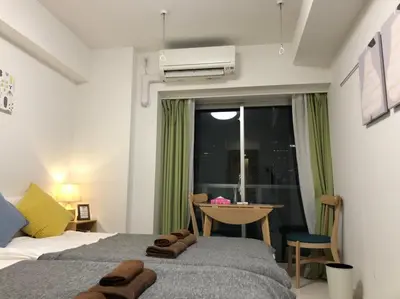 a bedroom with two beds and a table and a window at \u30ea\u30d6\u30b7\u30c6\u30a3\u9326\u7cf8\u753a\u53c2\u756a\u9928\u4e0a\u5c64\u968e\u773a\u671b\u826f\u597d\u5317\u6b27\u30eb\u30fc\u30e0, Akihabara 6mins, Tokyo 8 mins, Direct to Narita Airport \u6210\u7530\u7a7a\u6e2f\u76f4\u9054 in Tokyo