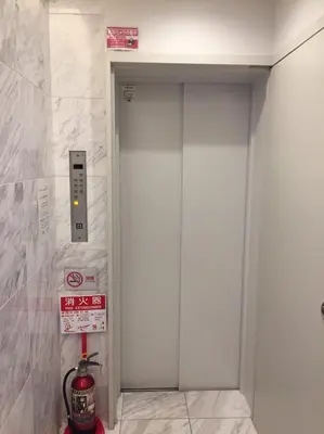 a white elevator in a building with a sign at Sakura Cross Hotel Akihabara in Tokyo