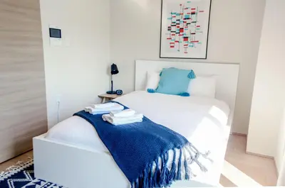 a white bed with a blue blanket on it at Dash Living Tsukiji in Tokyo