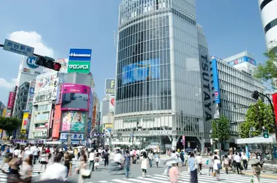 a crowd of people crossing a busy city street at the b sangenjaya in Tokyo